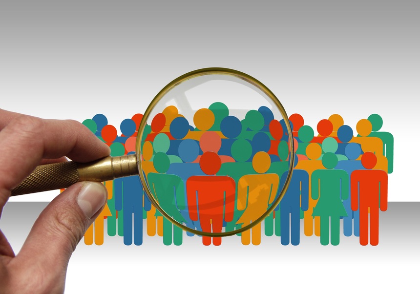 Grupo de muñecos de personas bajo una lupa